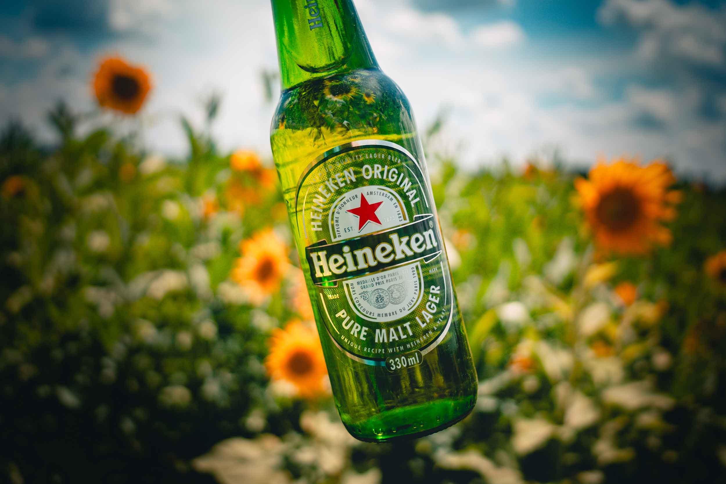 Garrafa Heineken em campo de girassol 